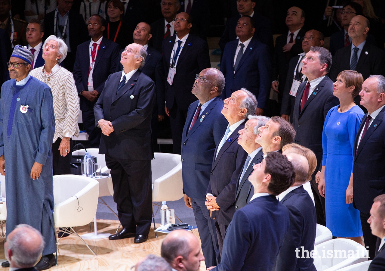 The world leaders gathered for the opening session of the inaugural Paris Peace Forum all look to the sky as an aerial photograph is taken to mark this historic event.
