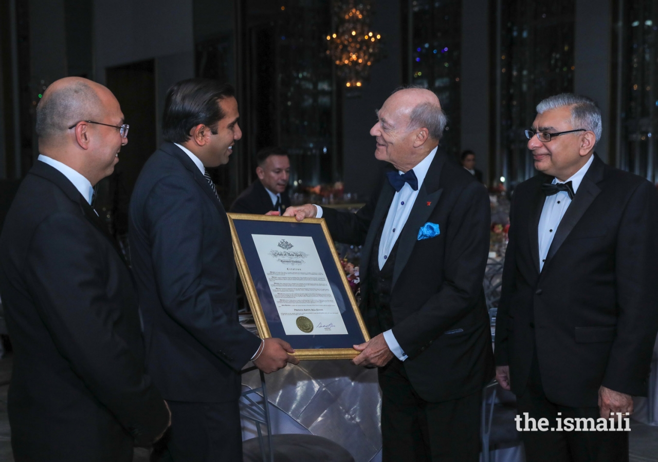 Hersh Parekh, Esq, representing the Office of Governor Andrew M. Cuomo, presents Prince Amyn  with a State of New York Executive Chamber Citation, as Barkat Fazal, President of the Ismaili Council for the USA looks on.