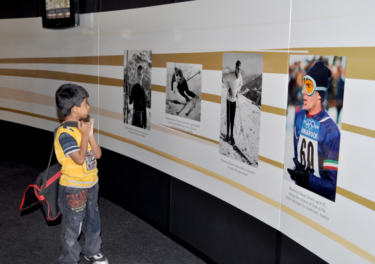 A boy is drawn to photographs of a younger Mawlana Hazar Imam, who skied at the 1964 Winter Olympics in Innsbruck, Austria.