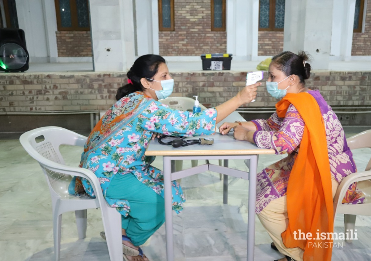 A volunteer takes the temperature of a patient at the vaccination centre.