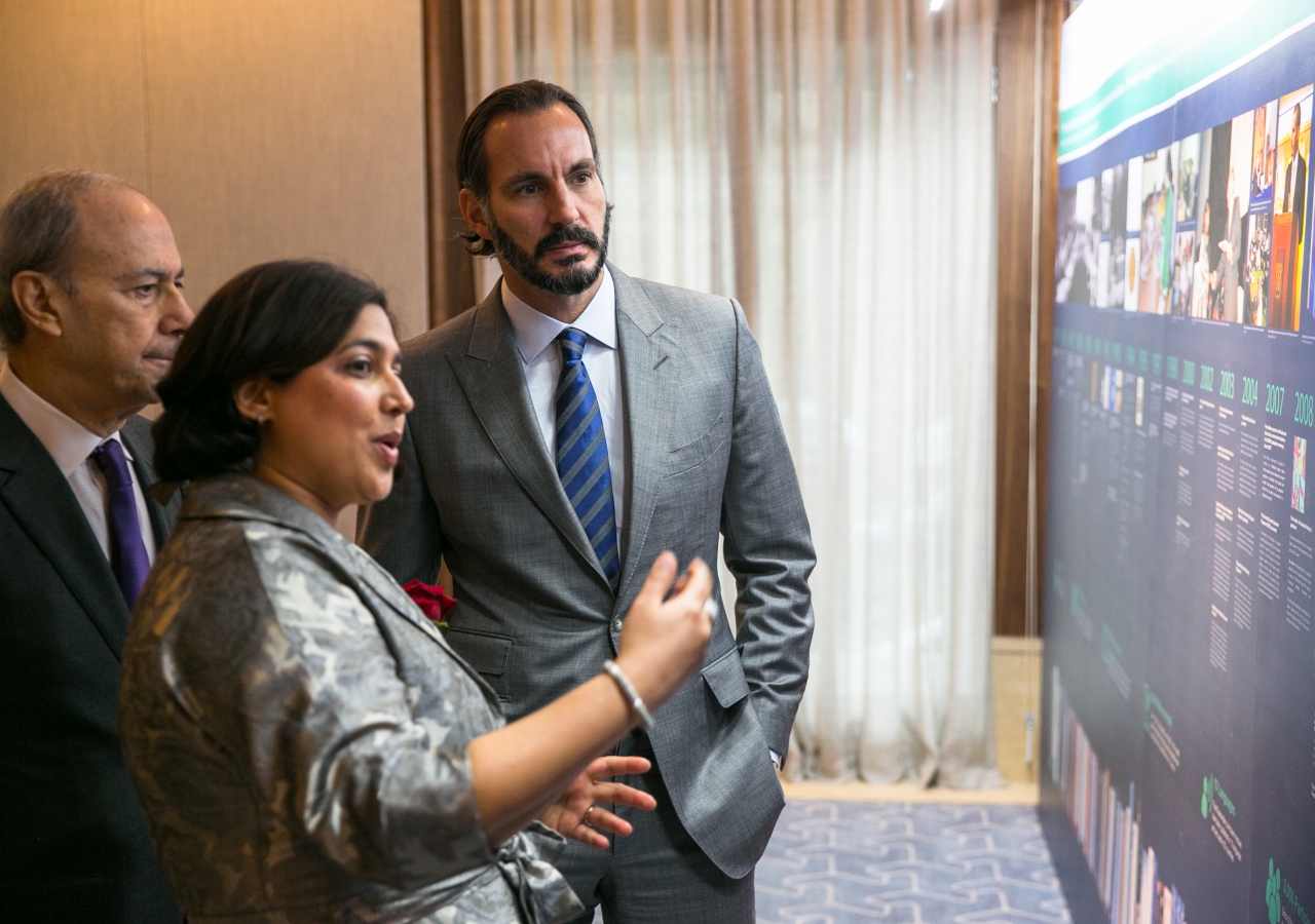 Salima Bhatia, Head of Communications at the IIS, presents to Prince Rahim an illustrated timeline display showcasing key milestones in the 40-year history of the Institute