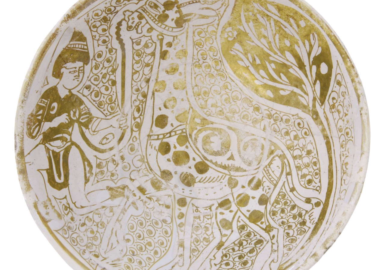 Ceramic dish with lustre decoration; it portrays a giraffe accompanied by its groom.