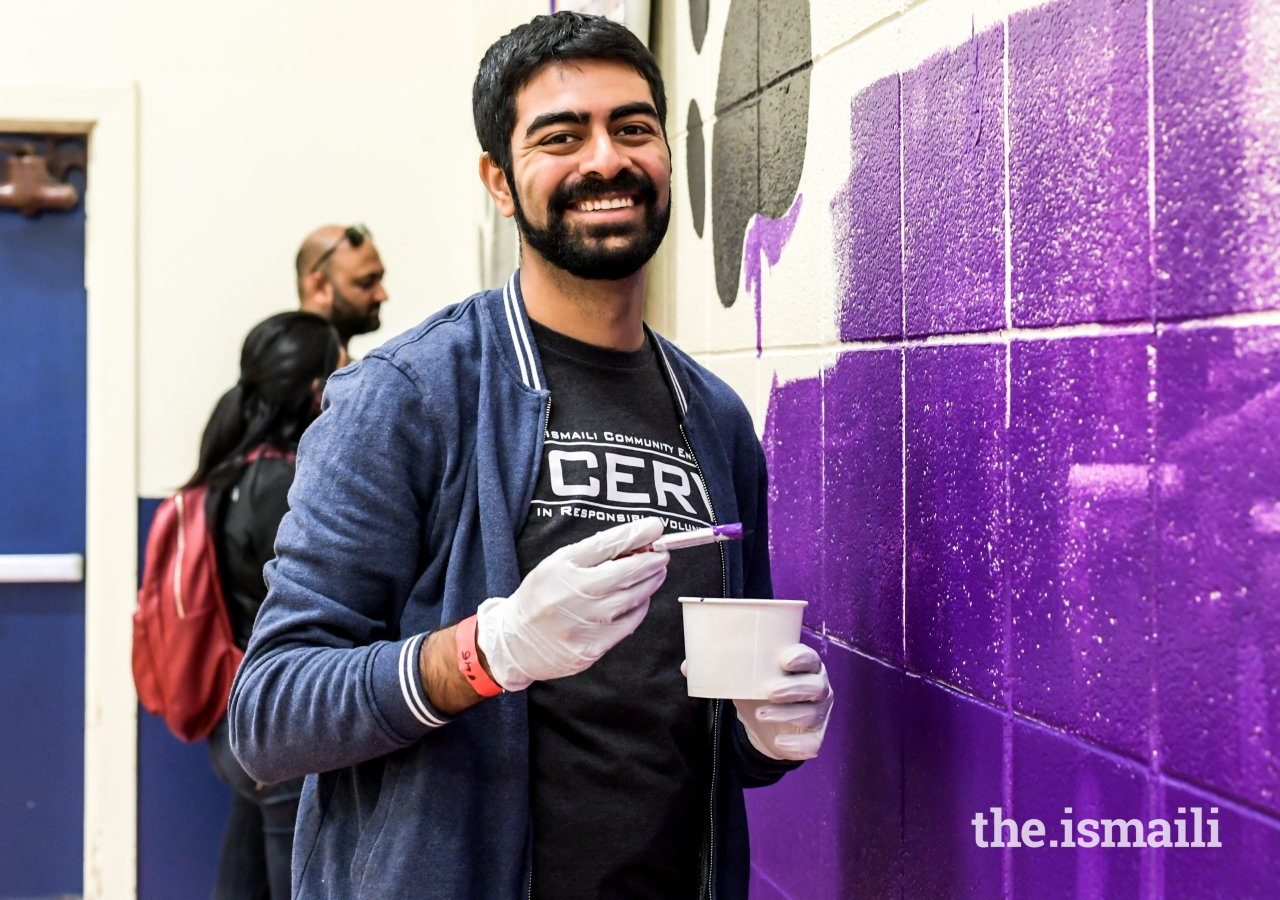 Samir Lakhani assists with painting a mural in the school gymnasium.