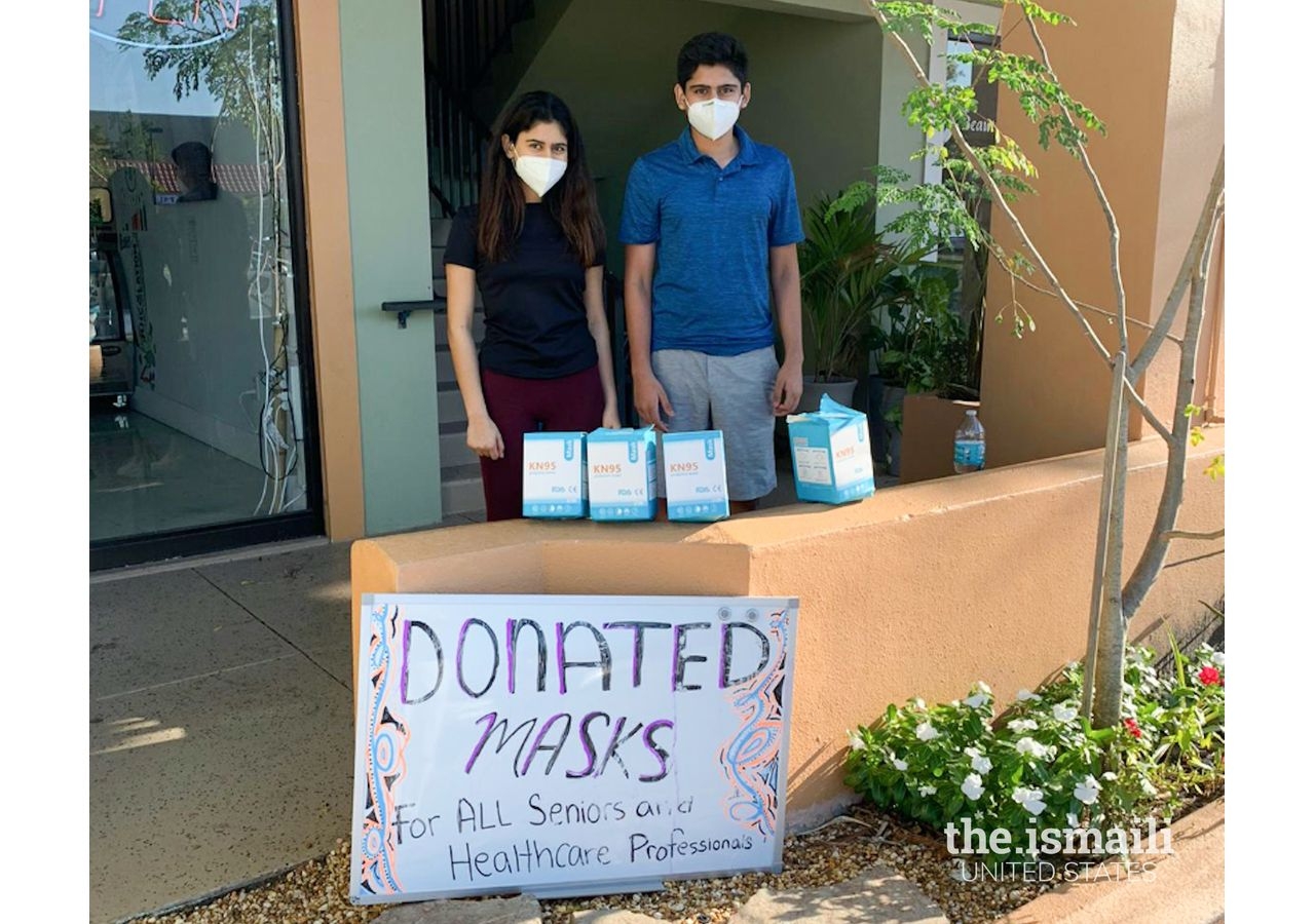 Samara (left) and Aliq (right) standing outside with boxes of masks set up to donate. 