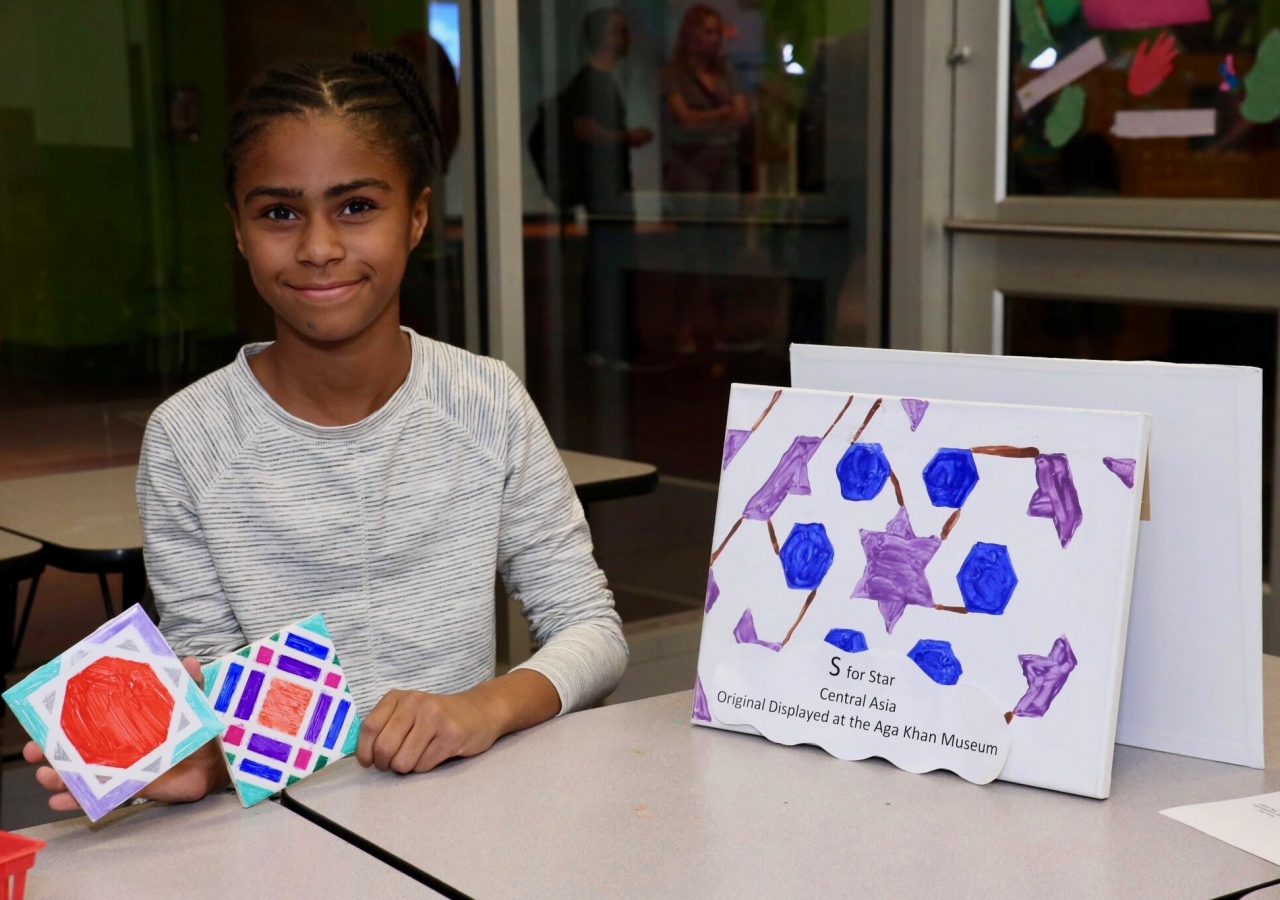 A young girl displays her geometric shape tile artwork, featuring traditional elements of Islamic art from the Aga Khan Museum publication, "Astounding ABC".