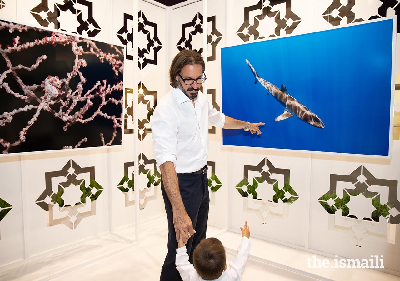 Prince Rahim shows Prince Irfan a photograph taken by Prince Hussain at the Nature Photographic Exhibition in Lisbon.