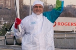 President Manji waves at the residents of Don Mills as he carries the Olympic Torch along York Mills Road in Toronto.
