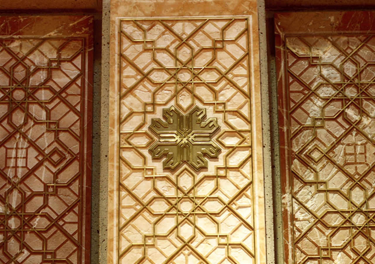 Sandblasted coral and rose marble panels inlaid with brass are used to form the mihrab, the Muslim architectural indication of the direction of prayer.