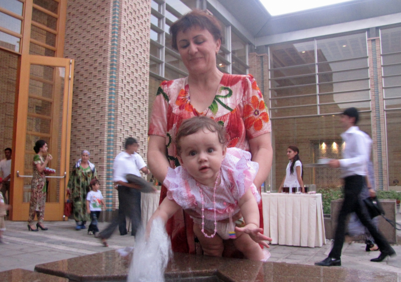 A child reaches to touch the water bubbling in a small fountain of the Ismaili Centre, Dushanbe courtyard.