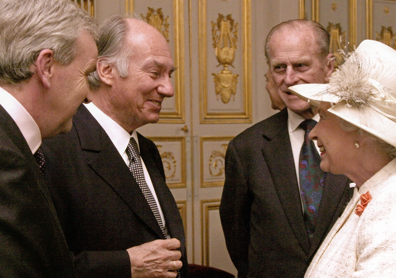 Mawlana Hazar Imam being invested "Knight Commander of the British Empire" (KBE) by Queen Elizabeth II on 5 April 2004. Duke Edinburgh is overlooking.