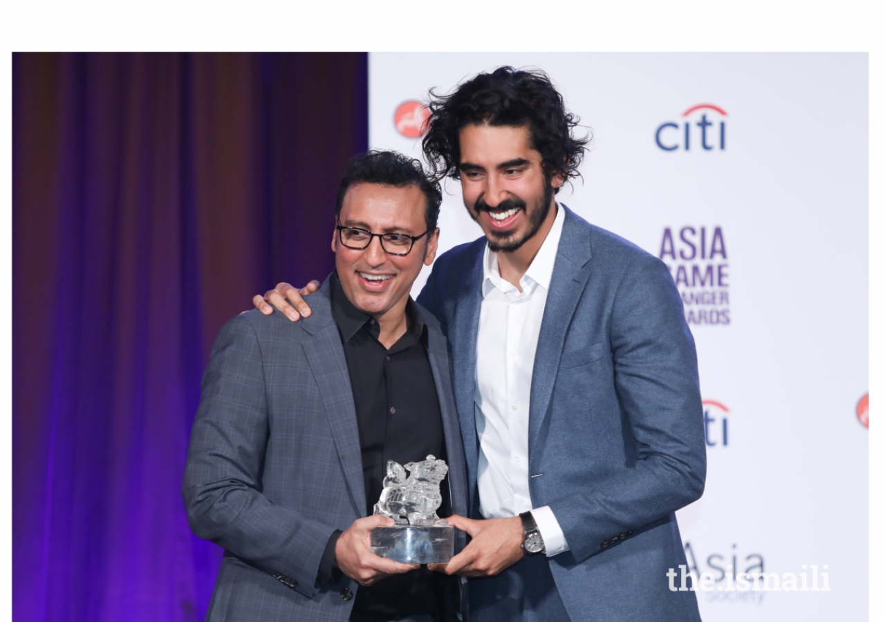 Aasif Mandvi presents Dev Patel with an Asia Game Changer Award.
