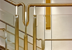Detail of the handrail in stainless steel, brass and plate glass, which runs along the main stair.