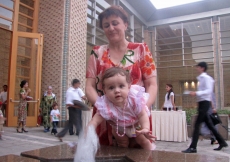 A child reaches to touch the water bubbling in a small fountain of the Ismaili Centre, Dushanbe courtyard.