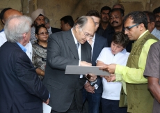 Mawlana Hazar Imam points out details on an archival photograph of the Qutb Shahi Heritage Park with Prince Aly Muhammad and Iliyan watching closely. AKDN / Ahmed Charania