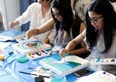 Participants of a workshop hosted by the International Art Gallery paint on canvas at an event promoting doing art together.