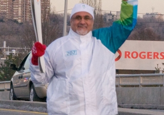 President Manji waves at the residents of Don Mills as he carries the Olympic Torch along York Mills Road in Toronto.