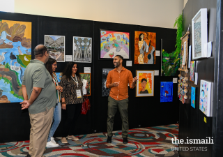 A visual artist explains his art to Jamati members at the Southwest United States Ismaili Arts Festival Art Gallery.
