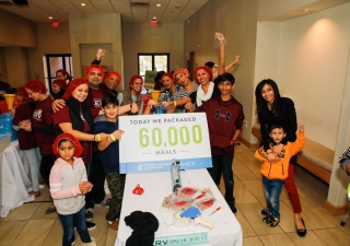 Volunteers of all ages celebrate as they exceed the goal of packing 60,000 meals in celebration of 60 years of Imamat.