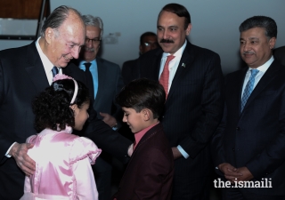Mawlana Hazar Imam in a light moment with children presenting bouquets.