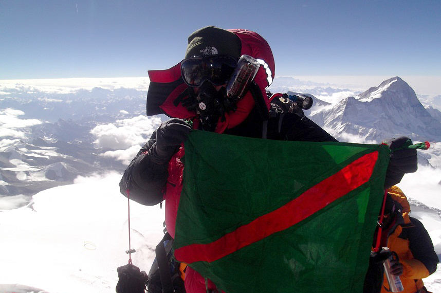 Samina Baig, the first Ismaili woman to reach the top of Mount Everest, proudly holds up the Ismaili flag on the summit of the highest mountain in the world. Photo: Mirza Ali